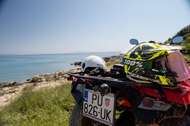 Helmets on a quad with the turquoise Adriatic behind