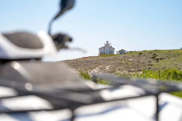 Coastal lighthouse seen past a parked quad
