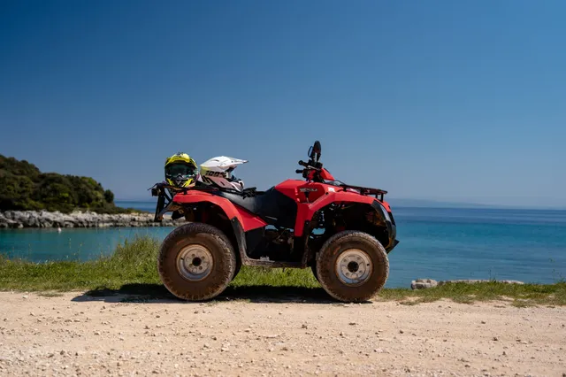 Red Kymco quad parked by the turquoise sea