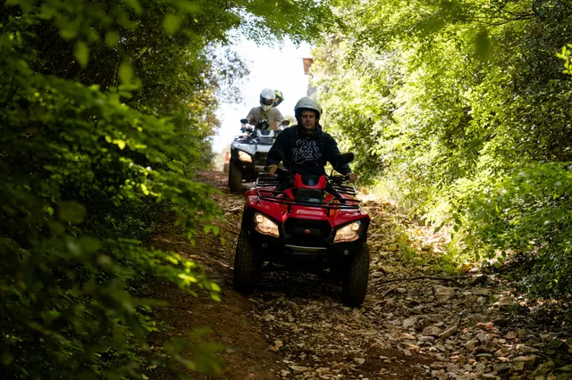 Red quad on a dappled rocky forest trail