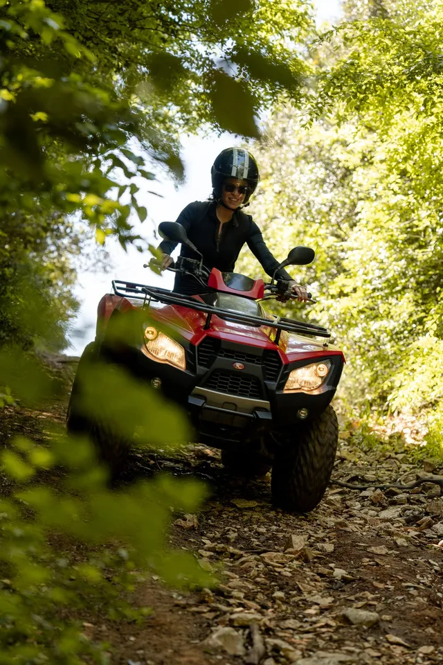 Rider on a red quad in dappled forest light