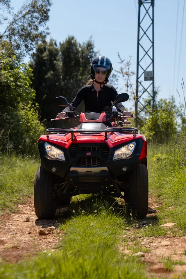 Rider on a red quad in a grassy meadow
