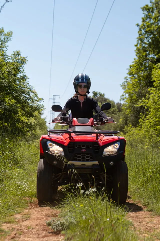 Rider on a red quad on a green trail